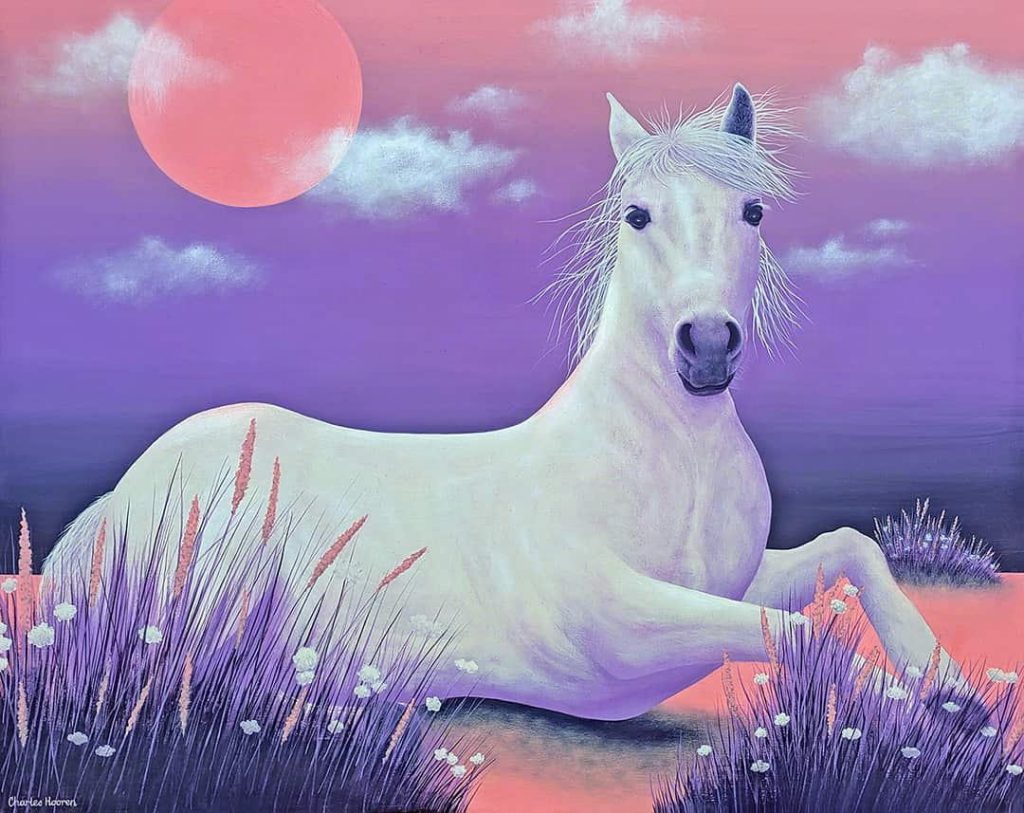 White mare resting peacefully underneath the rose sky